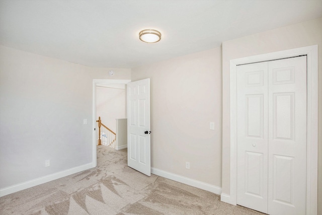 unfurnished bedroom featuring a closet and light carpet