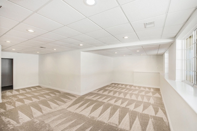 carpeted empty room featuring a drop ceiling