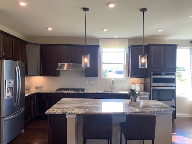 kitchen with sink, hanging light fixtures, stainless steel appliances, a center island, and a wealth of natural light