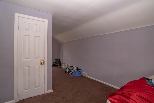 bonus room with dark carpet and vaulted ceiling