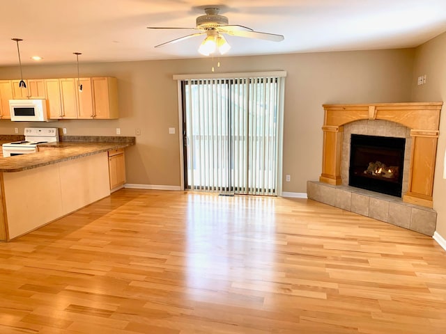 unfurnished living room with baseboards, light wood-type flooring, and a ceiling fan