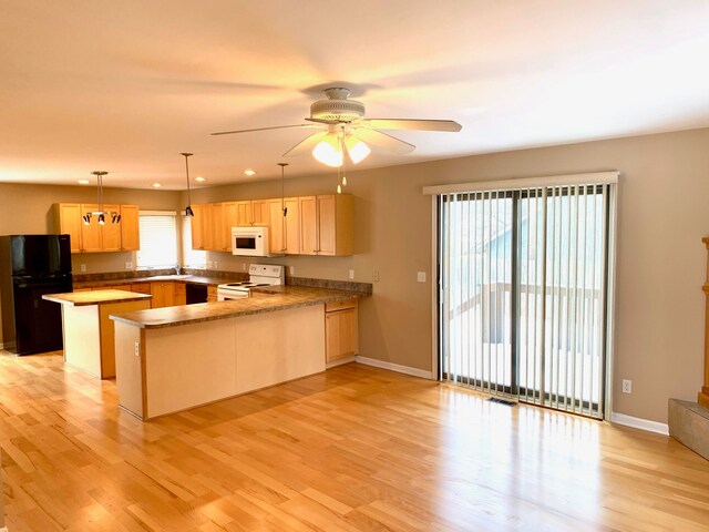 kitchen with black appliances, a peninsula, and light wood-type flooring