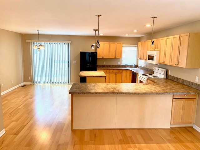 kitchen featuring light wood-style floors, a peninsula, light brown cabinetry, black appliances, and a sink