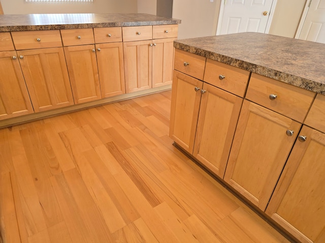 kitchen featuring light wood-type flooring, light brown cabinets, and dark countertops