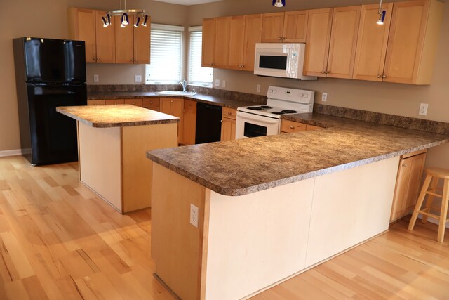 kitchen featuring black appliances, a sink, a center island, light wood-style floors, and a peninsula