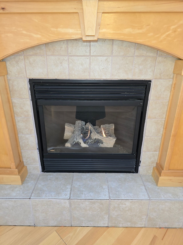 details featuring a tile fireplace and wood finished floors