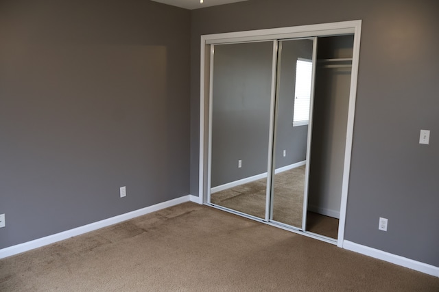 unfurnished bedroom with a closet, baseboards, and carpet