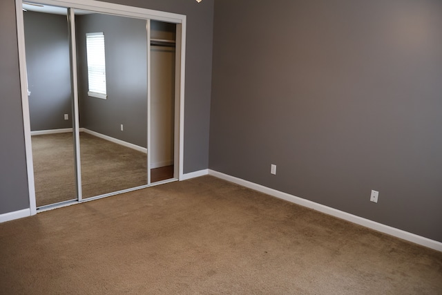 unfurnished bedroom with a closet, baseboards, and carpet flooring