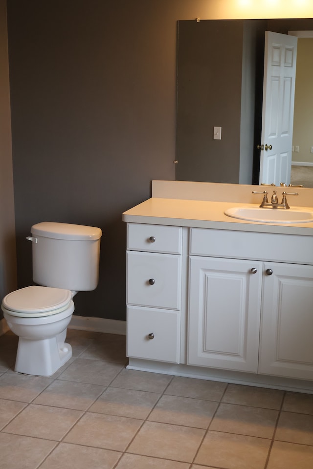 half bath with tile patterned floors, vanity, baseboards, and toilet