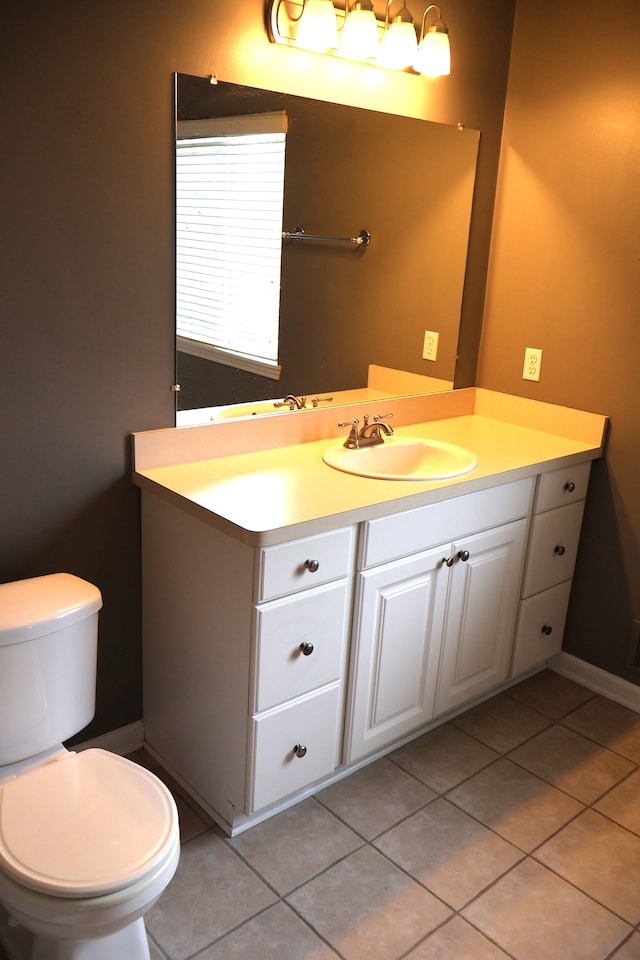 half bathroom featuring tile patterned flooring, toilet, and vanity