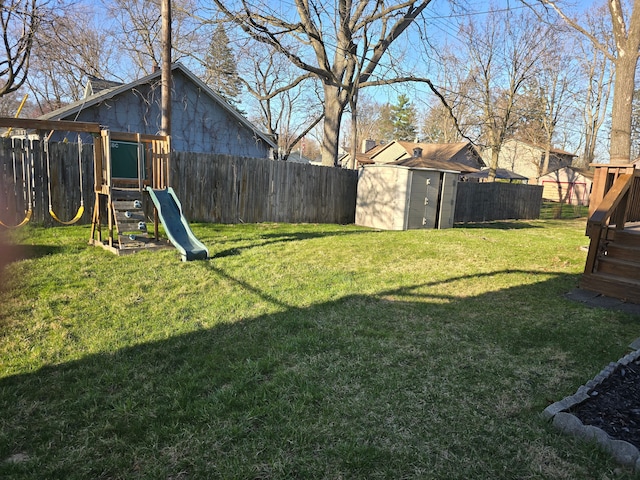view of yard with a fenced backyard, a playground, an outbuilding, and a storage unit