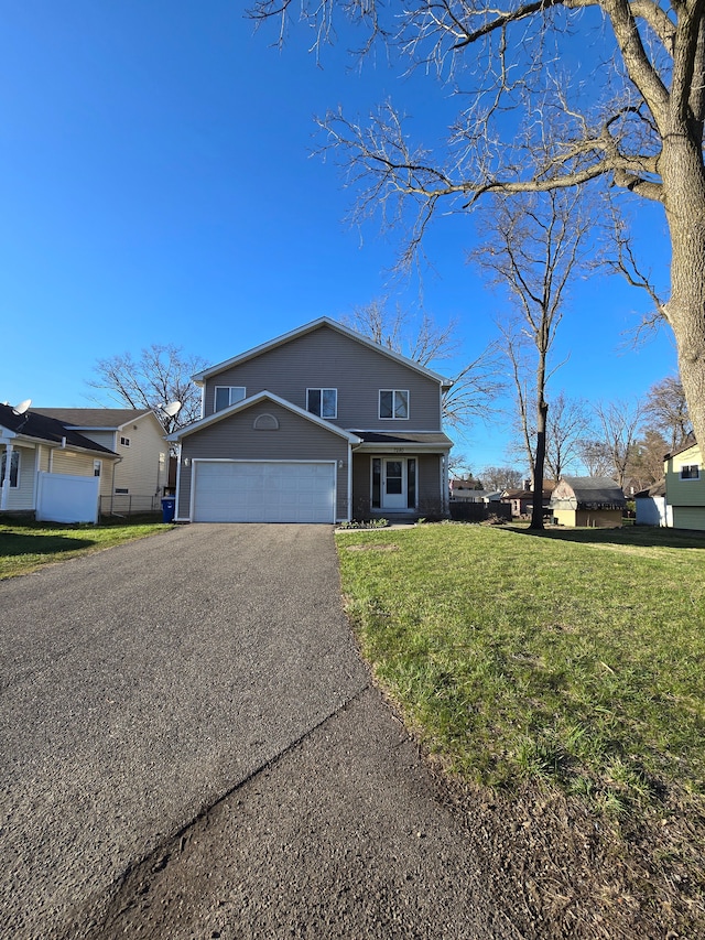 traditional home with a front yard, fence, a garage, and aphalt driveway