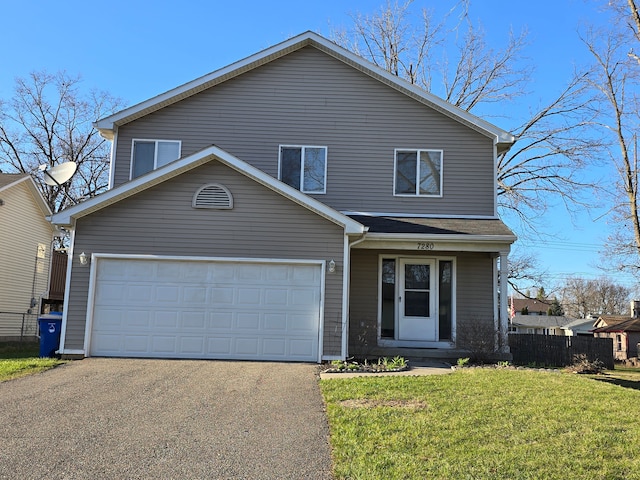 traditional-style house with a front lawn, fence, an attached garage, and driveway