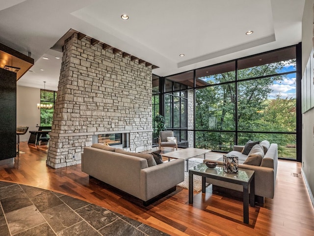 living room with floor to ceiling windows, a stone fireplace, and a chandelier