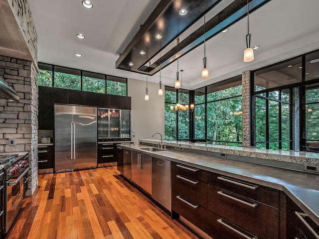 kitchen with pendant lighting, sink, light hardwood / wood-style flooring, dark brown cabinets, and high end appliances