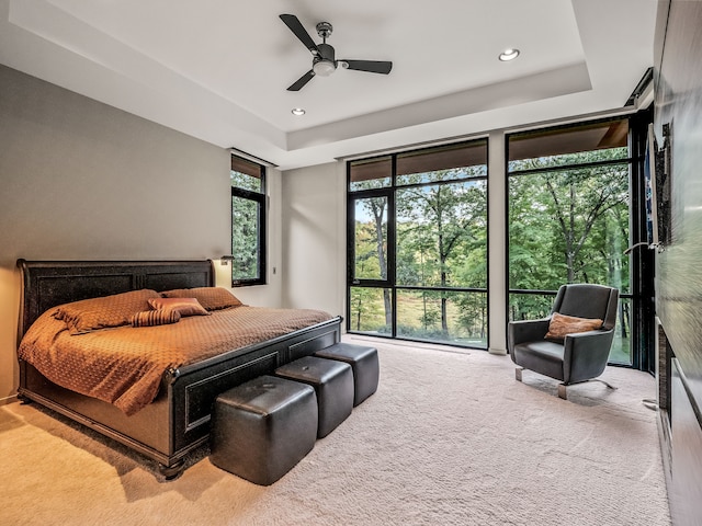 carpeted bedroom featuring a tray ceiling and ceiling fan