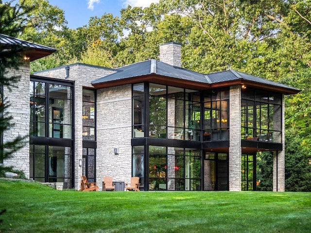 rear view of property featuring a yard and a sunroom