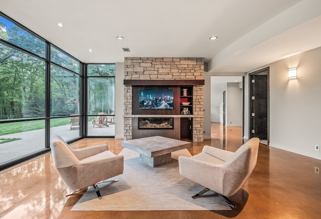 living room featuring a stone fireplace, floor to ceiling windows, and a healthy amount of sunlight