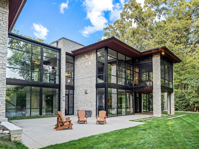 back of house featuring a yard, a patio area, and a sunroom