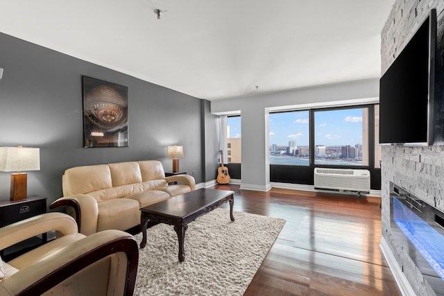 living room with dark wood-type flooring, a wall mounted air conditioner, and a fireplace