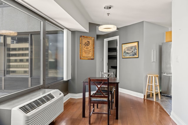 dining area with a wall unit AC and dark hardwood / wood-style floors