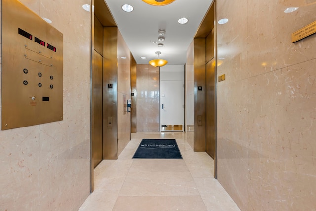 hallway with tile walls and light tile patterned flooring