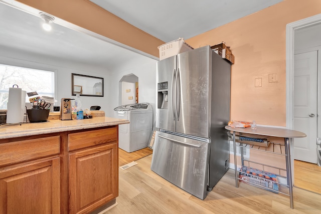 kitchen featuring light hardwood / wood-style flooring, washer / dryer, and stainless steel fridge