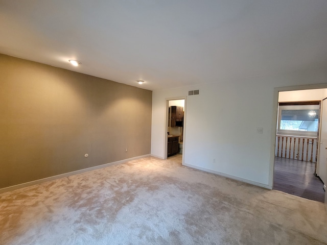 empty room with visible vents, light carpet, and baseboards