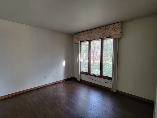 unfurnished room featuring baseboards and dark wood-style flooring