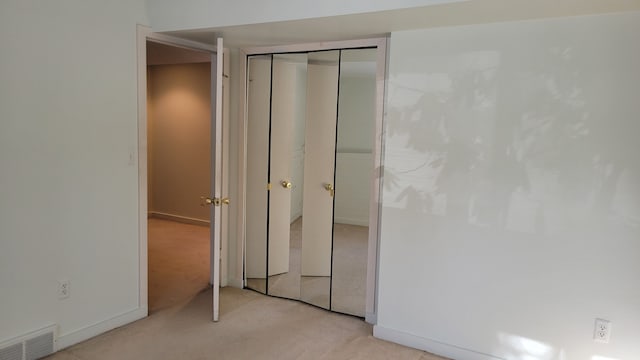 unfurnished bedroom featuring baseboards, visible vents, a closet, and light carpet