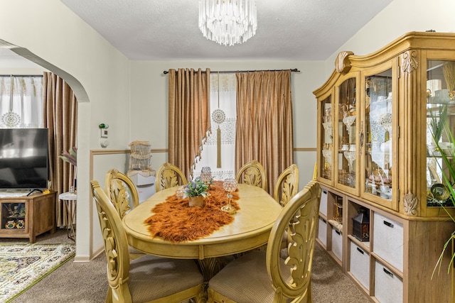 carpeted dining space featuring a textured ceiling and a notable chandelier