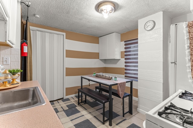 kitchen featuring sink, a textured ceiling, white cabinets, white appliances, and backsplash