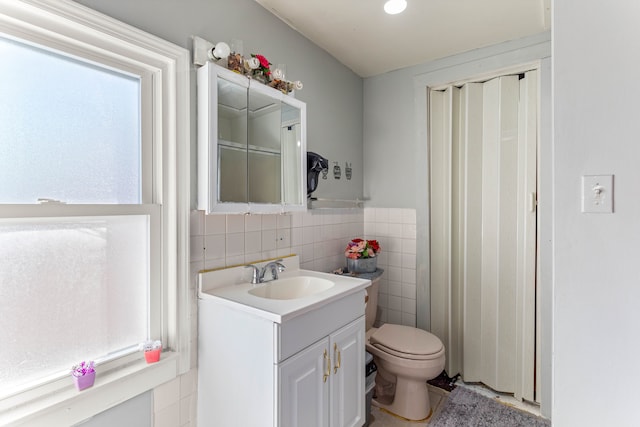 bathroom featuring vanity, tile walls, and toilet