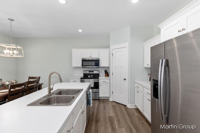 kitchen with a sink, decorative backsplash, light countertops, white cabinets, and appliances with stainless steel finishes