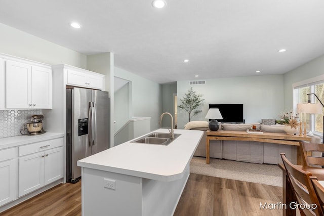 kitchen featuring wood finished floors, stainless steel fridge with ice dispenser, visible vents, and a sink