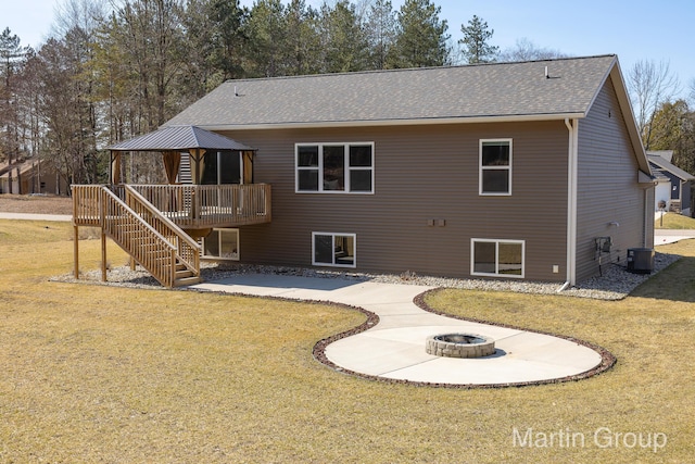 rear view of property featuring a gazebo, stairway, a lawn, and a fire pit