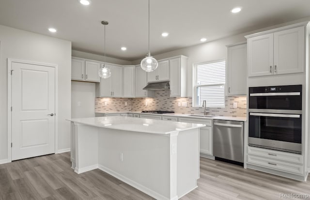 50050 Bluebell St, Canton, MI 48188 - kitchen with stainless steel appliances, under cabinet range hood, light wood finished floors, light countertops, and a kitchen island