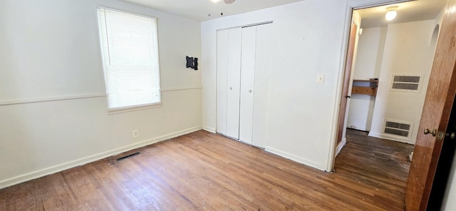 unfurnished bedroom featuring wood finished floors, a closet, and baseboards