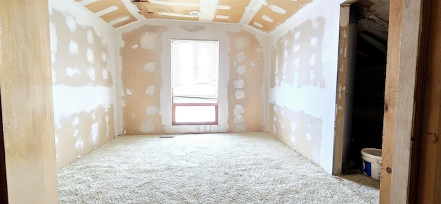 empty room with healthy amount of natural light, lofted ceiling, and carpet flooring