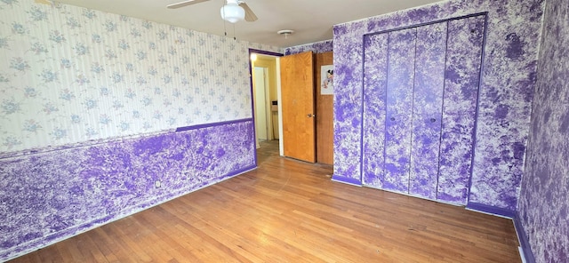 empty room featuring wallpapered walls, wood finished floors, and ceiling fan