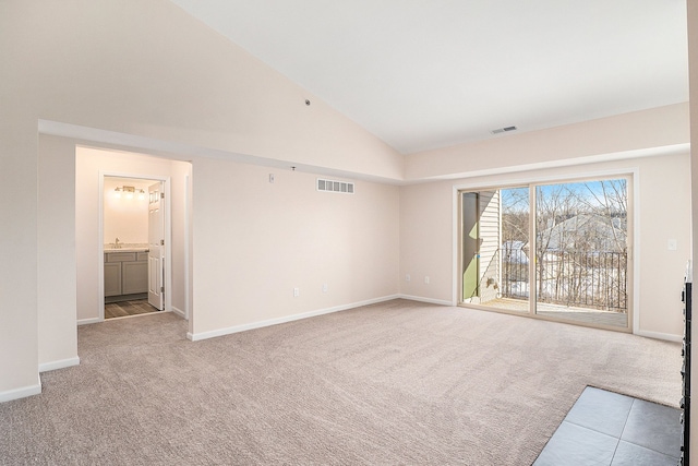 unfurnished living room with sink, light colored carpet, and high vaulted ceiling