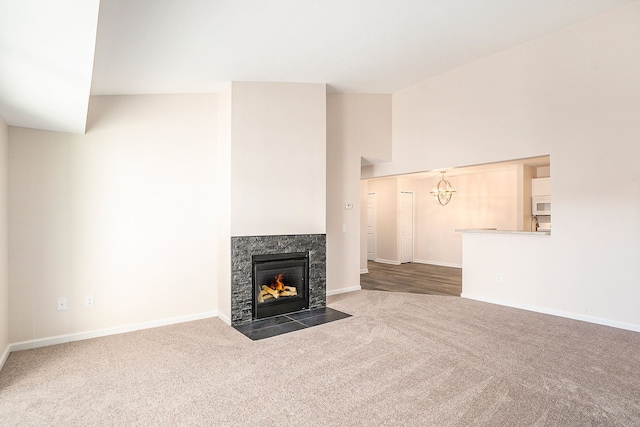 unfurnished living room featuring a high end fireplace, high vaulted ceiling, and dark colored carpet