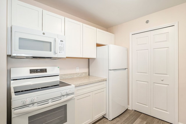 kitchen featuring light wood-type flooring, white cabinets, and white appliances