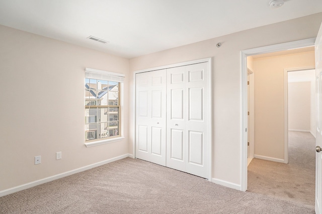 unfurnished bedroom with light colored carpet and a closet