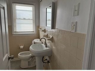 bathroom featuring tile walls and toilet