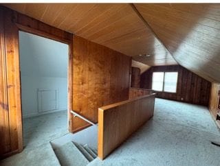 additional living space with vaulted ceiling, light colored carpet, wood ceiling, and wood walls