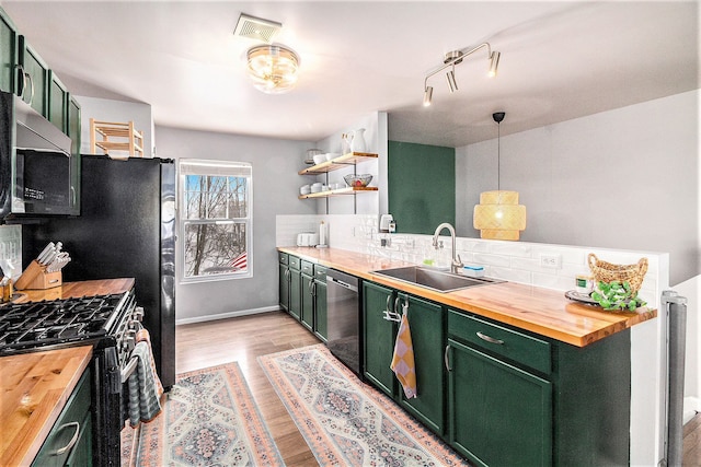 kitchen with sink, butcher block countertops, green cabinetry, hanging light fixtures, and stainless steel appliances