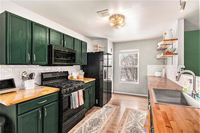 kitchen with wood counters, black appliances, and green cabinets