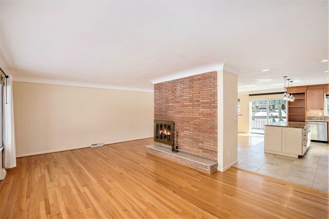 unfurnished living room with a brick fireplace and light wood-type flooring