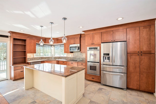 kitchen with appliances with stainless steel finishes, plenty of natural light, light stone counters, a kitchen island, and decorative light fixtures